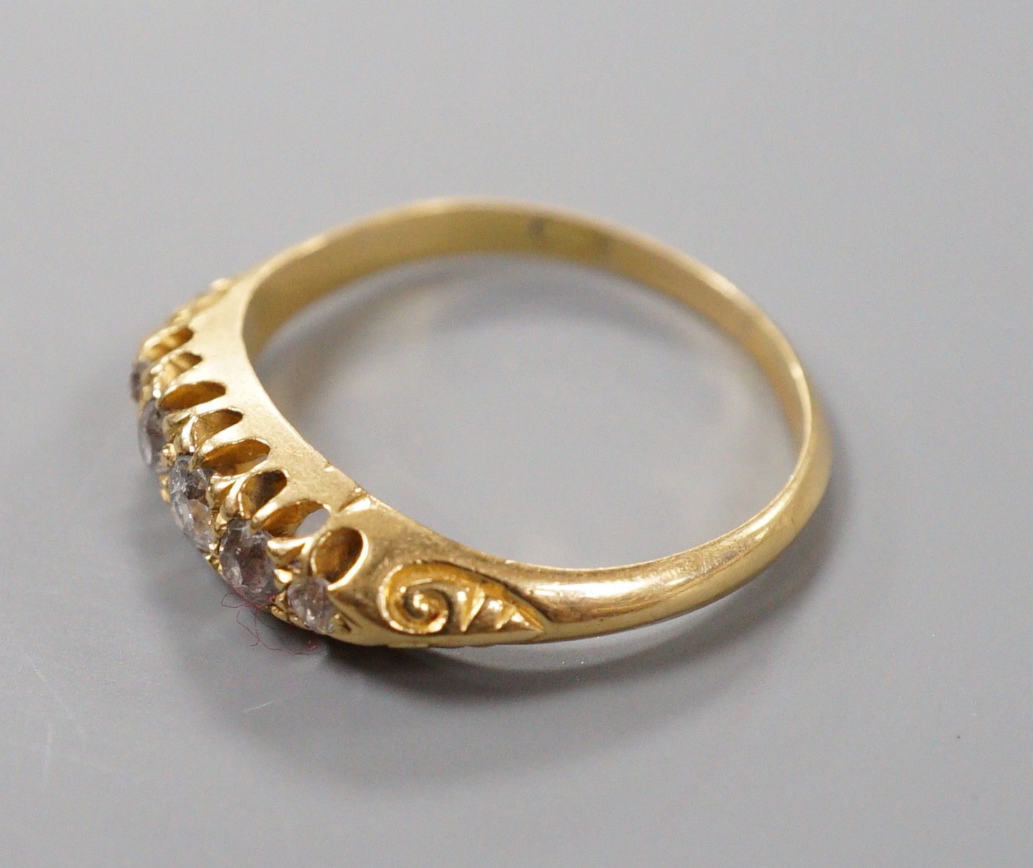 An Edwardian 18ct gold and graduated five stone diamond set half hoop ring, size M, gross weight 2.5 grams.
